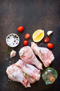 Fresh meat. Raw turkey shin, tomatoes, lemons and spices on a stone table. Copy space, top view flat lay background.