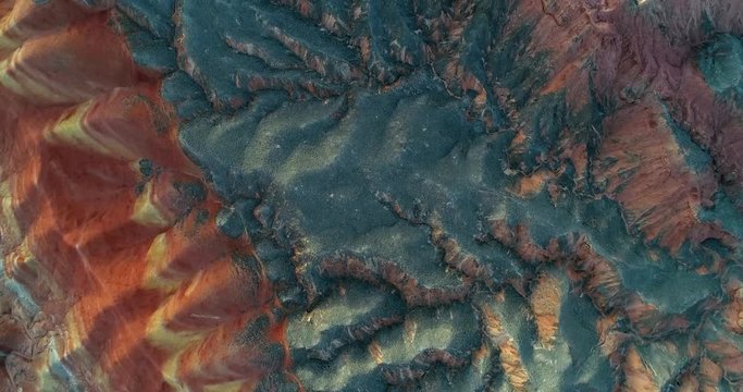 Flying over a minimalist mountain landscape. Aerial view on Rainbow mountains in Zhangye National Geopark covered with contrasting, multicolored pattern.