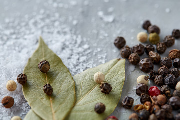 Composition of bay laurel leaf with peppercorn and salt isolated on dark background, top view, close-up, selective focus