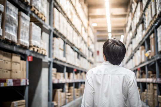 Young Asian man standing in warehouse choosing what to buy