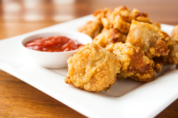 Sliced chicken fried served with ketchup on white plate. Crunchy snack. Favorite fast food.