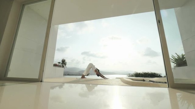Healthy woman practicing yoga exercises on outdoor terrace with sea landscape