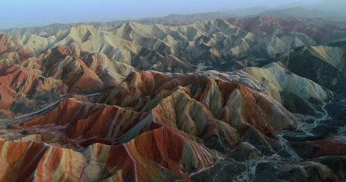 Flying drone over Rainbow mountains. Aerial view on most beautiful section of Zhangye Danxia Rainbow Mountains showing hills covered with multicolored pattern.