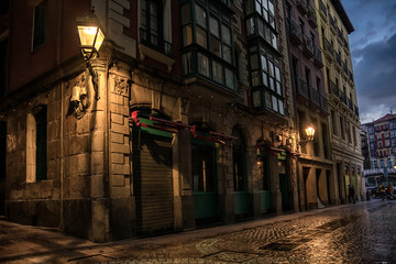 Narrow street corner with warm old lamp in the old city in Bilbao. Spain