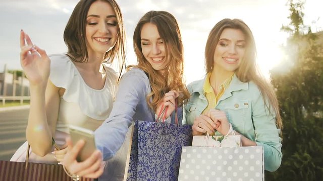 Three beautiful girls making selfie after shopping near mall at sunset. Shopping concept