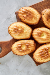 Almond cookies and raw almonds on wooden cutting board over white background, close-up, selective focus.