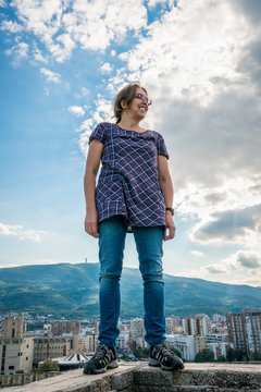 Woman standing on ancient wall with the city of Skopje in the background. Low angle position.