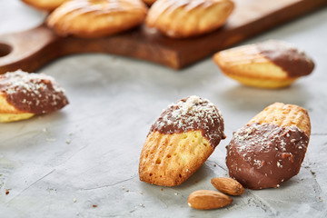 Almond cookies and raw almonds on wooden cutting board over white background, close-up, selective focus.