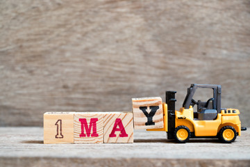 Toy forklift hold block Y to complete word 1may on wood background (Concept for calendar date 1 for...