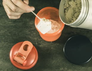 sports nutrition, a man puts himself a portion of protein, bcaa in a shaker, against a dark background, top view
