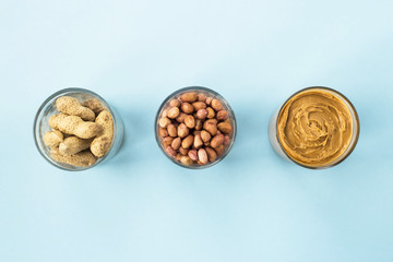 Three jars of peanut in a shell, peeled peas and vegan peanut butter. Cooking Natural Healthy Food Concept. Top view, flat lay