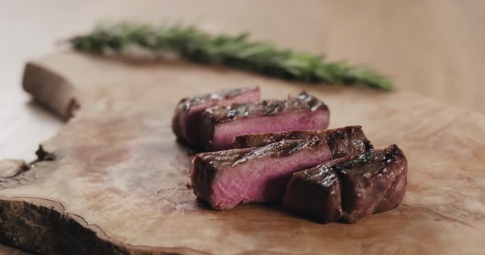 Slow motion slide sliced rare fillet mignon steak on wood board