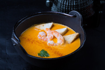 Orange asian seafood cream soup with prawns