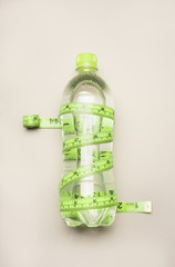 transparent bottle with water wrapped measuring tape on white background, healthy lifestyle concept...