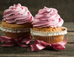 Closeup of cupcakes with vanilla, berries, pink and white cream, chocolate and sprinkles on wooden background. Selective focus. Sweet dessert tasty food concept muffin.