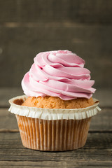 Closeup of cupcakes with vanilla, berries, pink and white cream, chocolate and sprinkles on wooden background. Selective focus. Sweet dessert tasty food concept muffin.