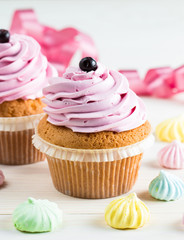 Closeup of cupcakes with vanilla, berries, pink and white cream, chocolate and sprinkles on wooden background. Selective focus. Sweet dessert tasty food concept muffin.