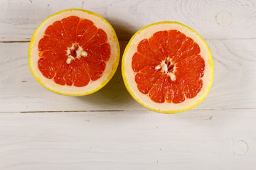 Halves of ripe grapefruit on white wooden table