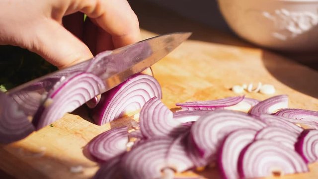 Rapidly Chopping Onion, Close-Up. Slow mothion. red onions close up. Female hands cut onions in kitchen. Macro shooting of red onions. The woman cuts onions on a wooden board.