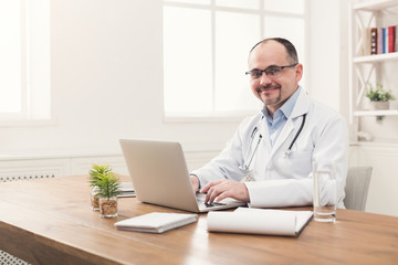 Portrait of doctor in glasses sitting at desktop