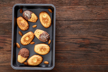 Freshly baked almond cookies on cooking tray over wooden background, top view, selective focus.