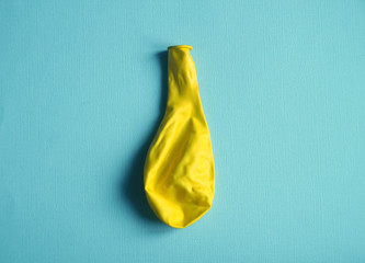 Deflated yellow balloon on blue background