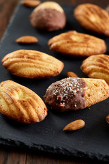 Freshly baked almond cookies on stone board over wooden background, top view, selective focus.