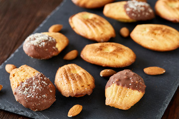 Freshly baked almond cookies on stone board over wooden background, top view, selective focus.