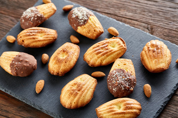 Freshly baked almond cookies on stone board over wooden background, top view, selective focus.