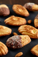 Freshly baked almond cookies on stone board over wooden background, top view, selective focus.