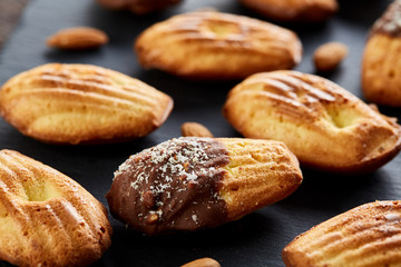 Freshly baked almond cookies on stone board over wooden background, top view, selective focus.