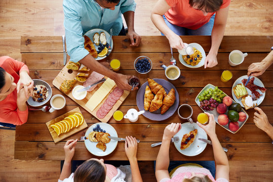 food, eating and family concept - group of people having breakfast and sitting at table