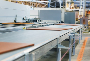 production, manufacture and woodworking industry concept - chipboards processing on conveyer at furniture factory workshop