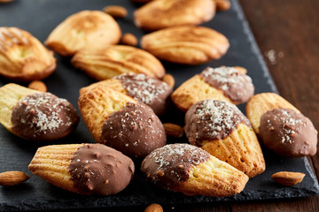 Freshly baked almond cookies on stone board over wooden background, top view, selective focus.