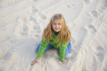 Little adorable girl playing on sand beach