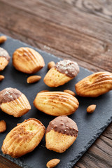 Freshly baked almond cookies on stone board over wooden background, top view, selective focus.