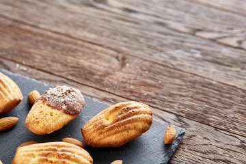 Fotobehang Freshly baked almond cookies on stone board over wooden background, top view, selective focus. © Aleksey