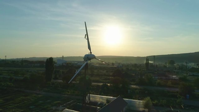Aerial shot: Small Wind Turbin over a sunset background. loop. Alternative renewable energy production