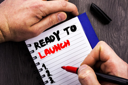 Handwritten text sign showing Ready To Launch. Conceptual photo Prepare New Product Promotion Start Release written on Notebook Book Man Writing Holding Pen wooden background.