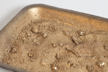 Golden nuggets on grungy wash pan with sand