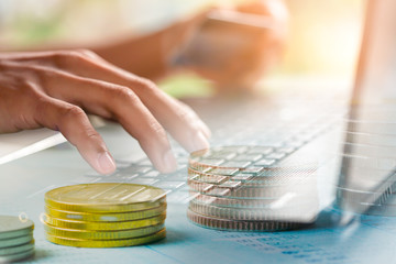 Double exposure Of hand typing laptop and  and rows of coins for finance and banking concept