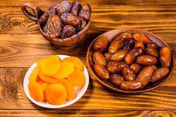Date fruits and dried apricots on wooden table