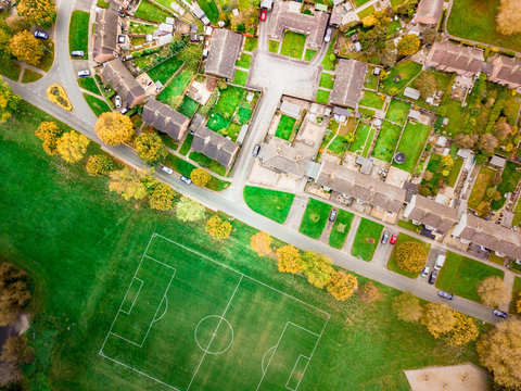 Aerial view of a football pitch, fields and homes on public recreation ground. Looking straight down on a sports playing field used for community matches