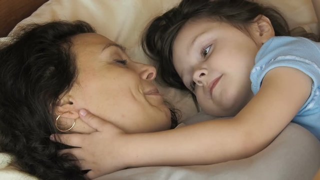 Happy family in bed. A happy mother is kissing a child.