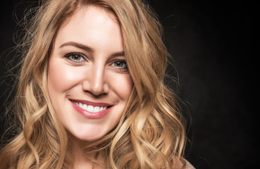 Portrait of an attractive young blonde woman on a black background.