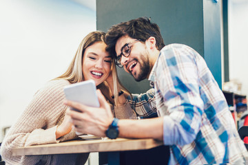 Obraz premium Young couple in indoor cafe using digital tablet