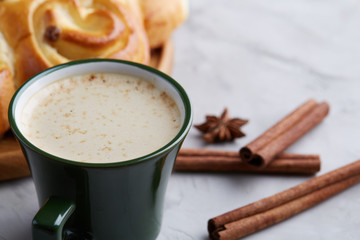Homemade rose bread, cup of coffee, anise and cinnamon on white textured background, close-up, shallow depth of field