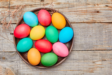 Plate with colorful easter eggs on wooden table