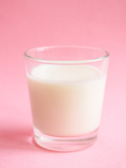 A glass of milk on pink background.