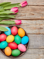 Colorful easter eggs and tulips on wooden background